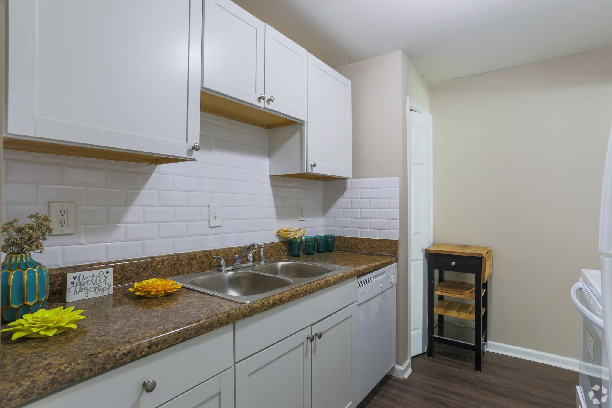 A kitchen with white cabinets and a brown countertop.